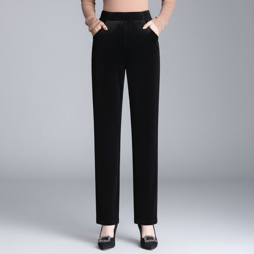 Black velvet pants worn by a person on a gray background