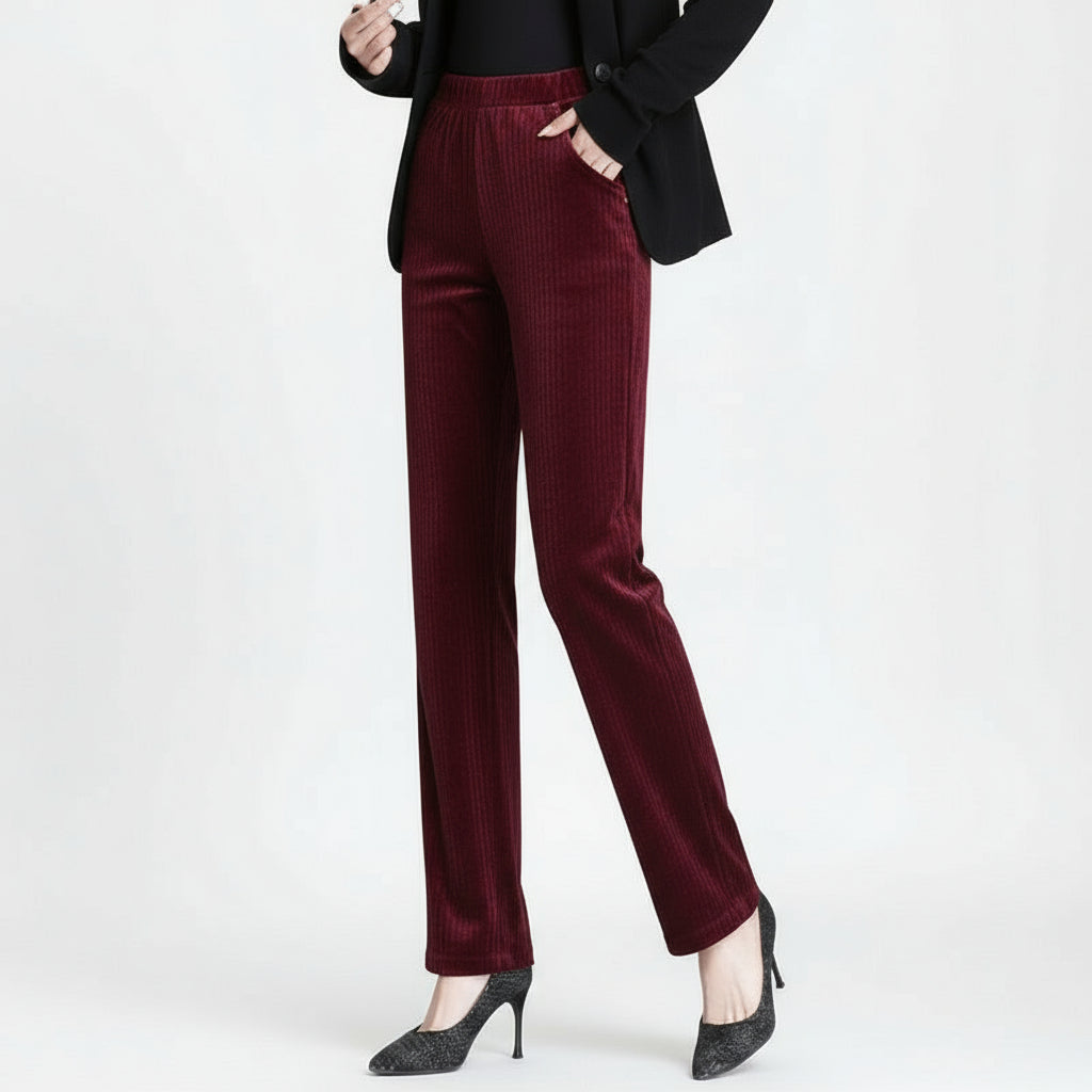 Burgundy velvet pants worn by a person on a gray background