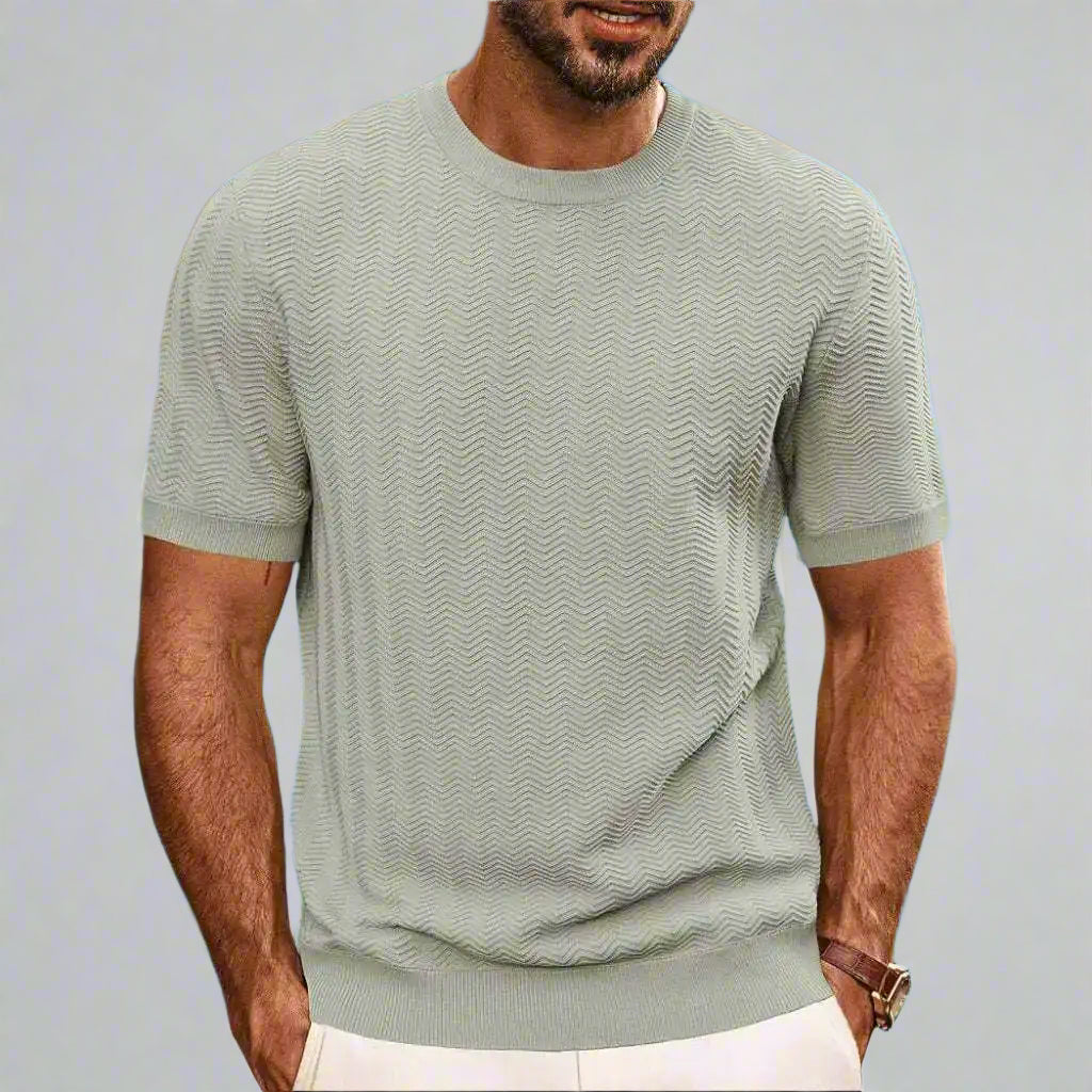 Man wearing a light green textured t-shirt with a beach background
