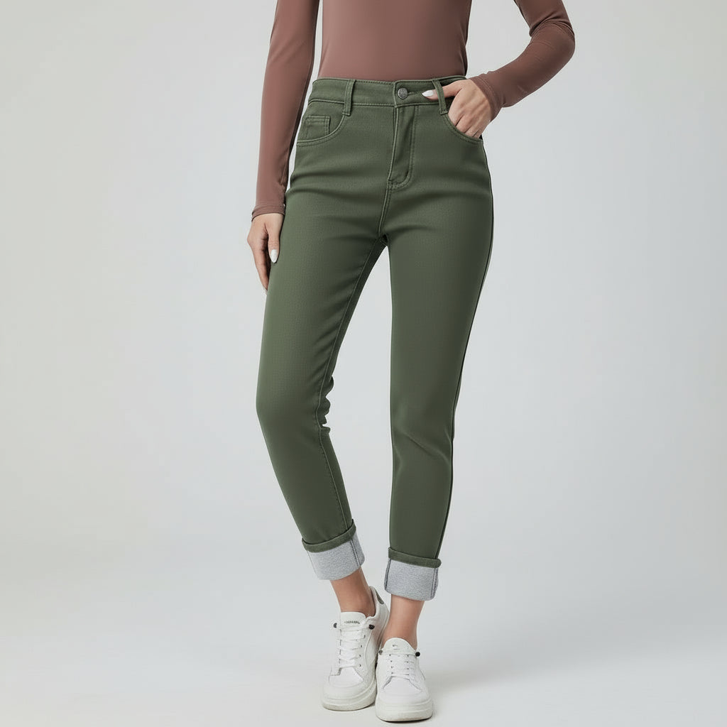 Person wearing green jeans and white sneakers on a plain background