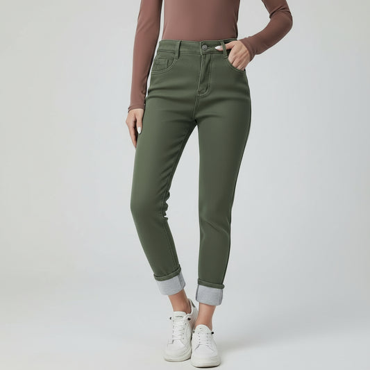 Person wearing green jeans and white sneakers on a plain background