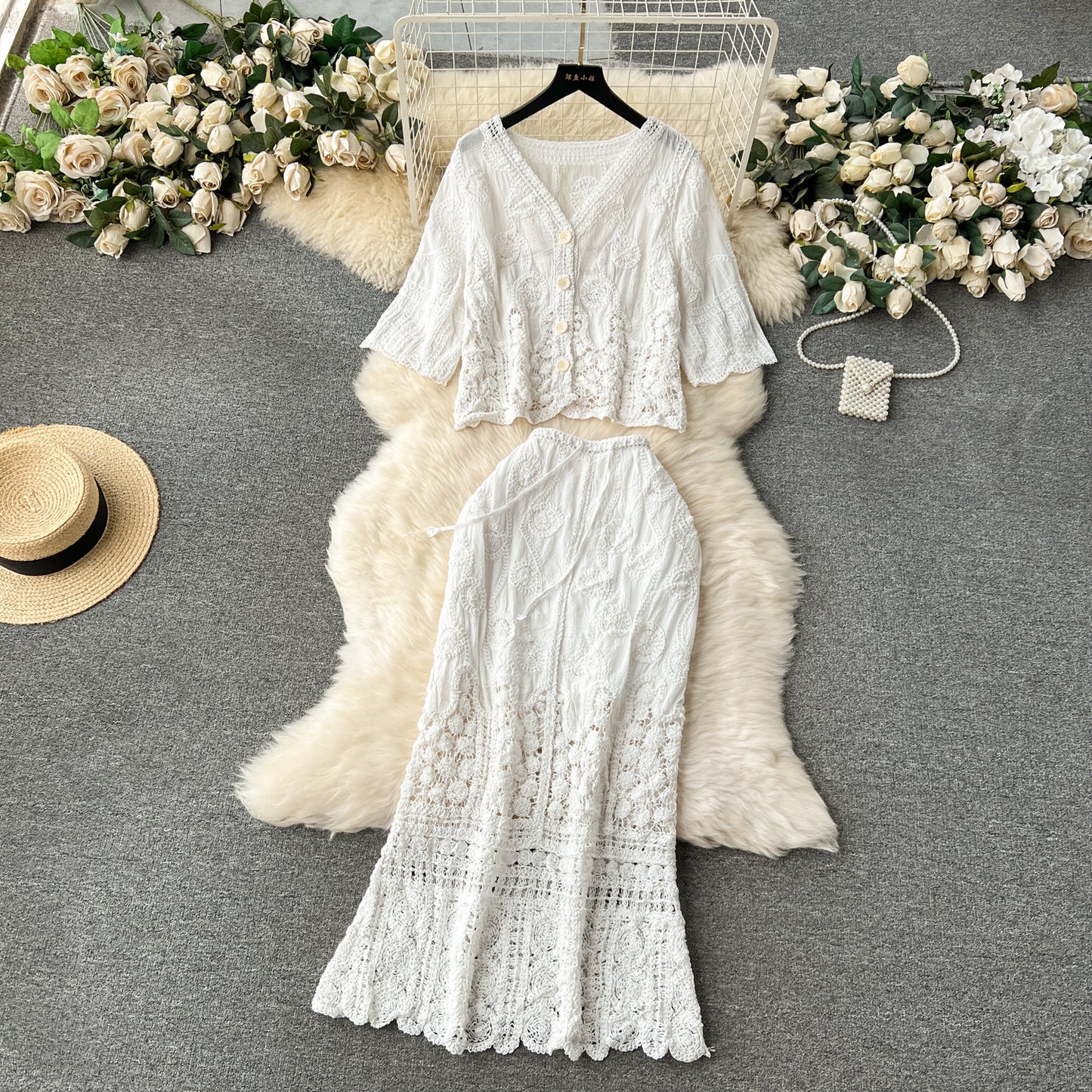 White lace outfit with a hat and flowers on a gray surface