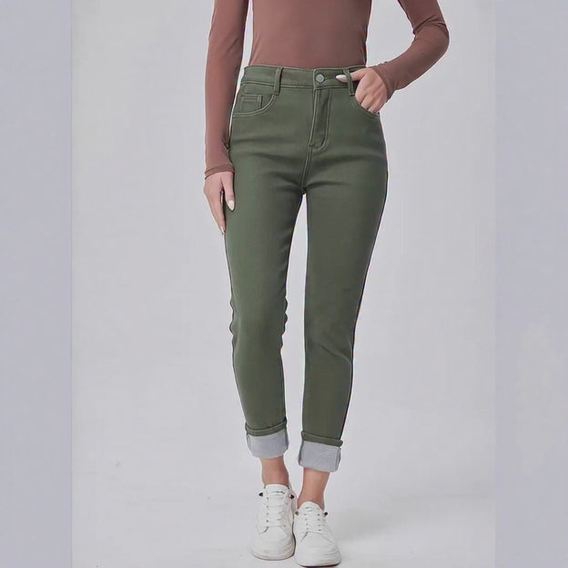 Person wearing green jeans and white sneakers on a plain background