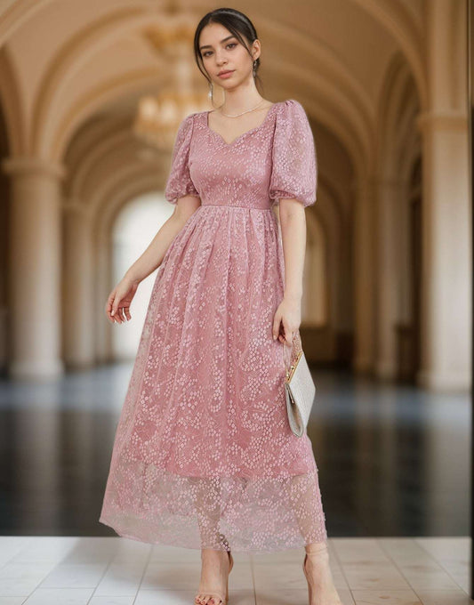 Woman in a pink lace dress standing in an elegant hallway
