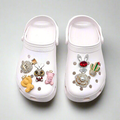 White clogs with decorative charms on a white background