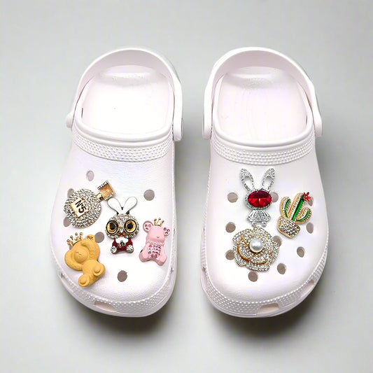White clogs with decorative charms on a white background