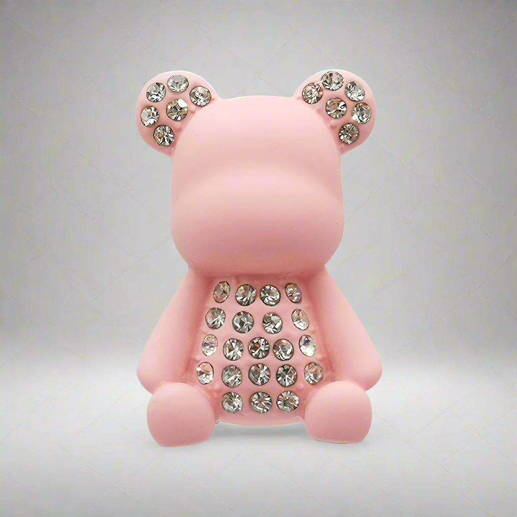 Pink teddy bear-shaped object with rhinestone details on a white background
