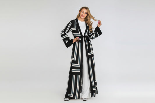 Woman wearing a black and white patterned long coat on a light gray background