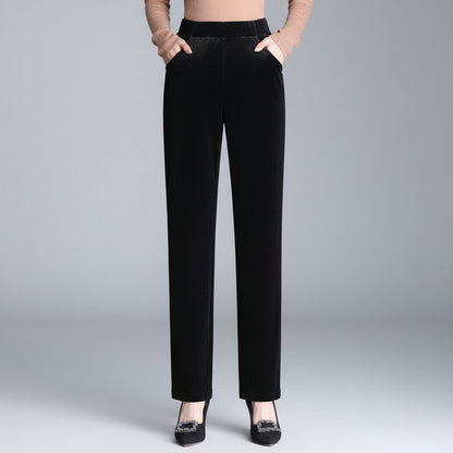 Black velvet pants worn by a person on a gray background
