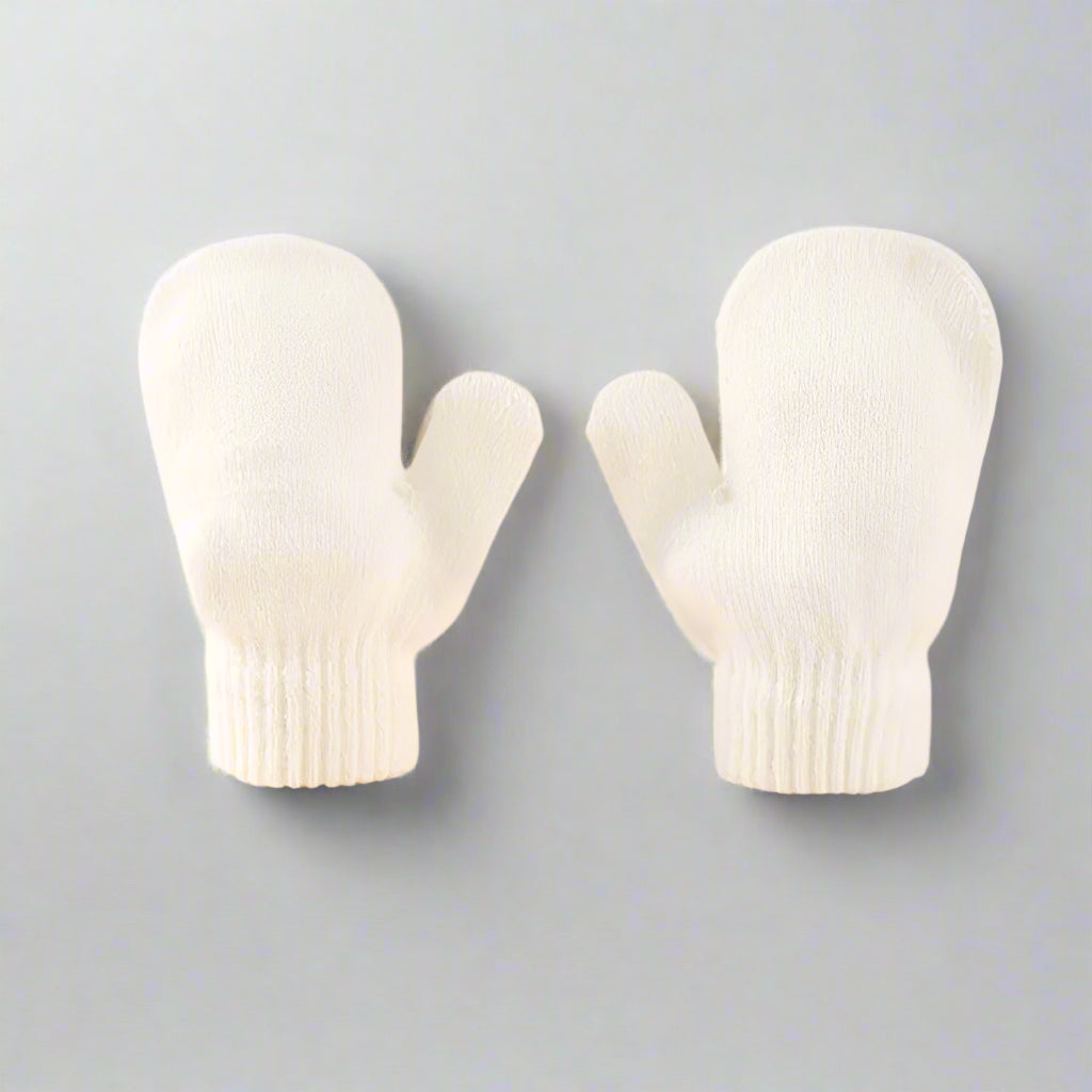 Pair of white baby mittens on a beige background