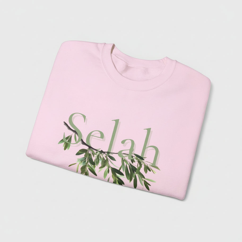 Folded pink sweatshirt with 'Selah' and green leaf design on a white background