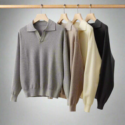 Four sweaters in gray, beige, and black hanging on wooden hangers against a white background.