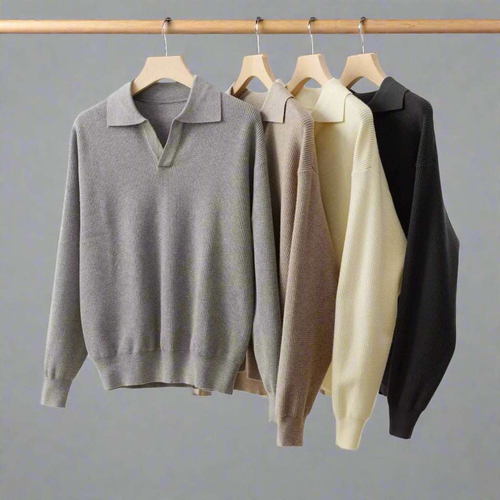 Four sweaters in gray, beige, and black hanging on wooden hangers against a white background.