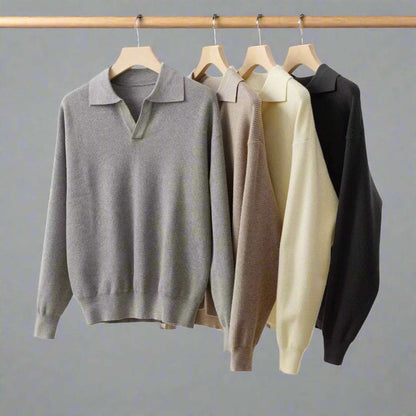 Four sweaters in gray, beige, and black hanging on wooden hangers against a white background.