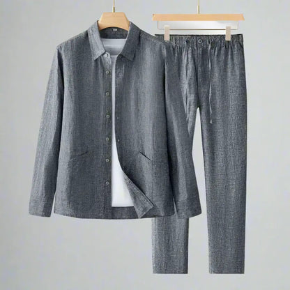 Gray shirt and pants set on hangers against a gray background
