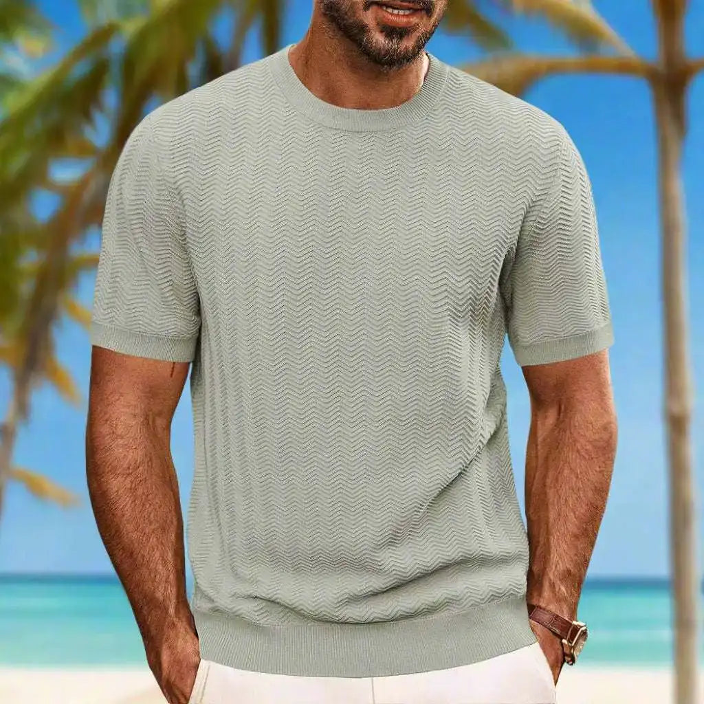 Man wearing a light green textured t-shirt with a beach background