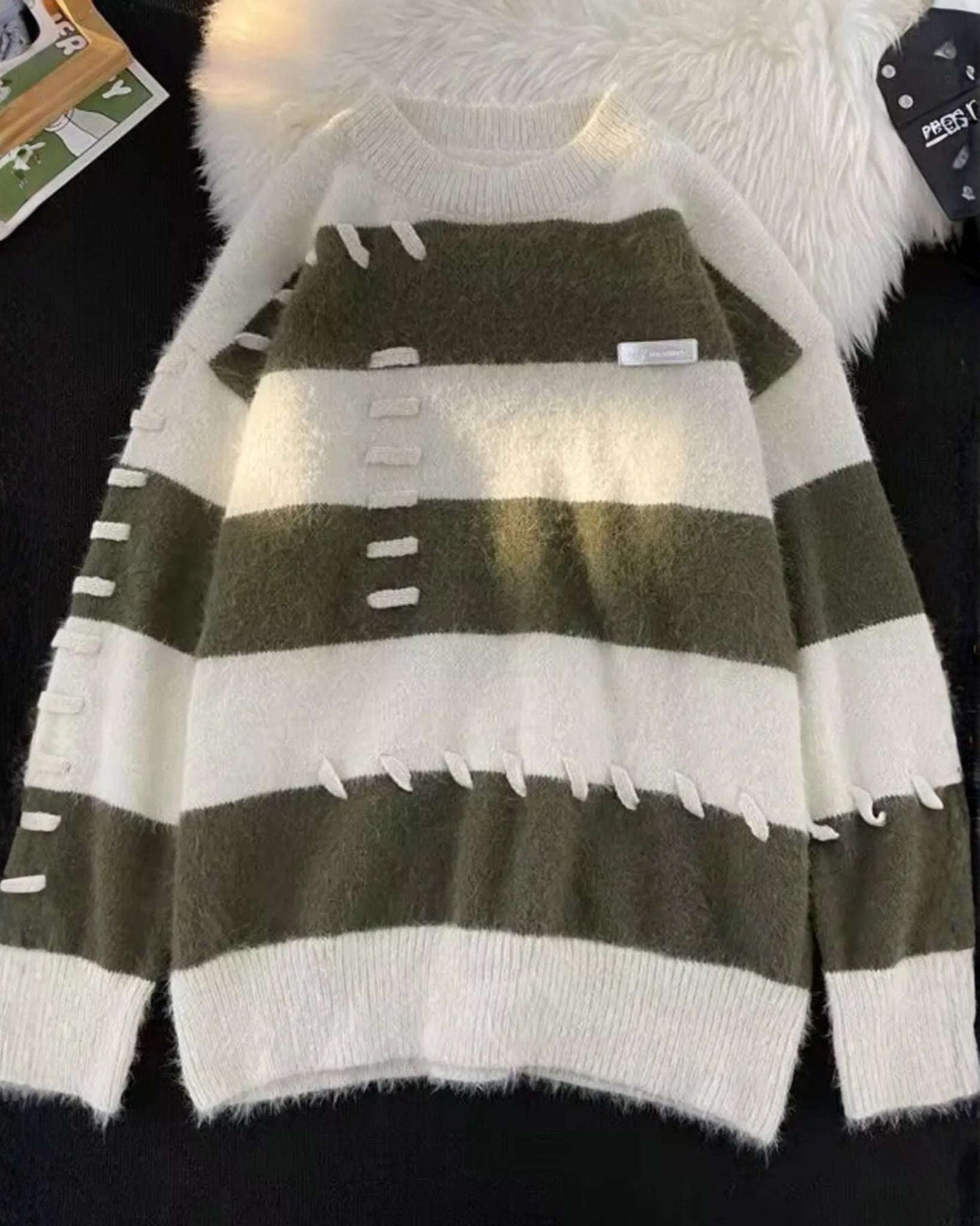 Green and white striped sweater with a fluffy white item in the background