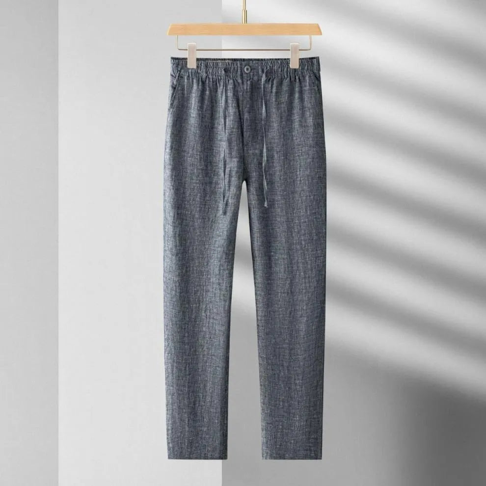 Blue denim pants hanging on a wooden hanger against a gray background