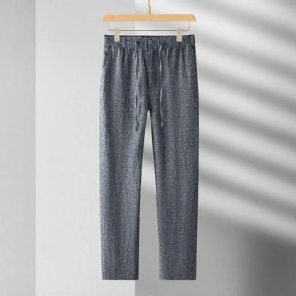 Blue denim pants hanging on a wooden hanger against a gray background