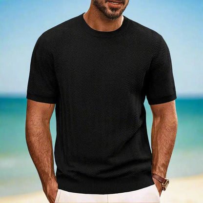 Man wearing a black t-shirt with a beach background