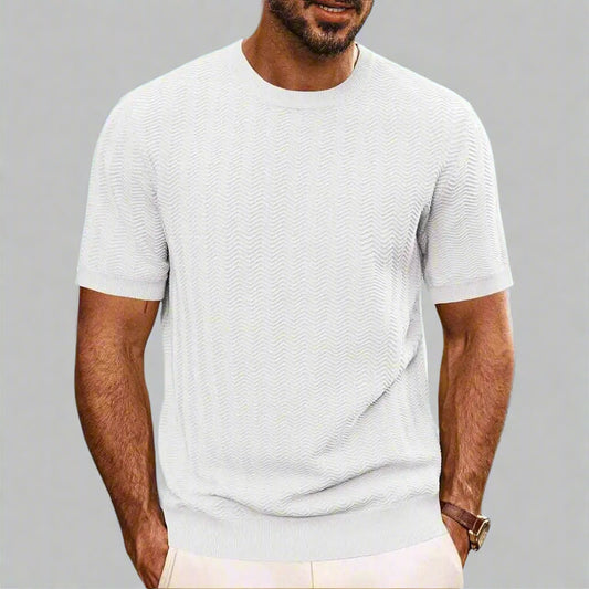 Man wearing a light gray t-shirt against a blurred natural background