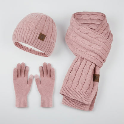 Pink knit hat, scarf, and gloves set on a light gray background