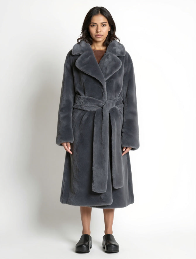 Woman wearing a long gray coat with a belt on a white background