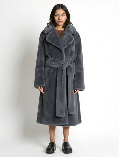 Woman wearing a long gray coat with a belt on a white background